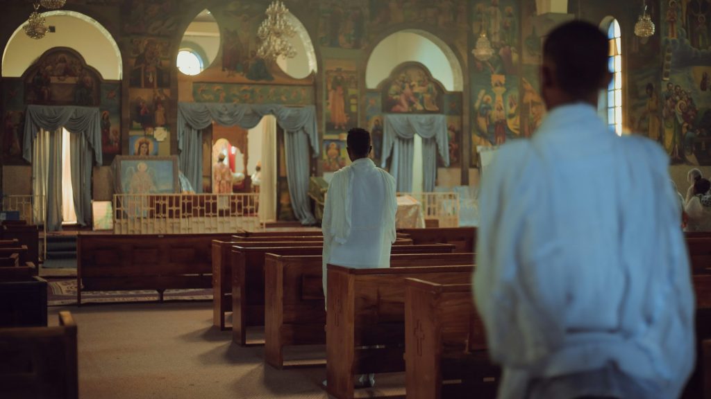 a man standing in front of a pew in a church
